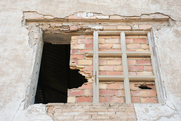 Broken bricked up window belonging to an abandoned industrial building.