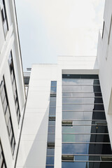 Obraz premium Large white building with huge dark and blue sales windows looking up clear blue clear sky