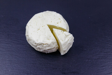 Soft Adyghe cheese on black slate background