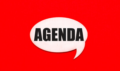 On a bright red background, a light wooden curly card with a dough AGENDA.
