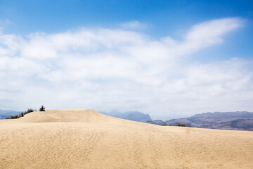 Blue sky and sand dunes with footprints.