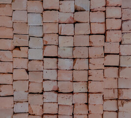 A stacked grid of red bricks of indian origin used in construction of buildings or walls