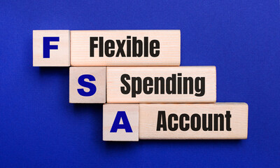 On a bright blue background, light wooden blocks and cubes with the text FSA Flexible Spending...