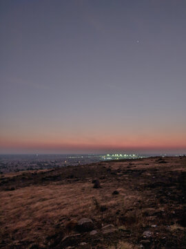A scenic hill top view of Gulbarga city after sunset in arid region of deccan india with illuminated street lights from far away being seen