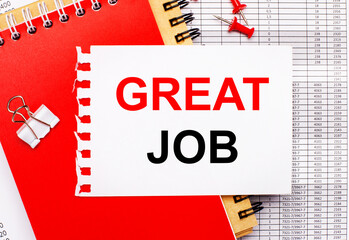 Against the background of the reports, there are red and brown notepads, a white paper clip, red buttons and a white sheet of paper with the text GREAT JOB. Business concept