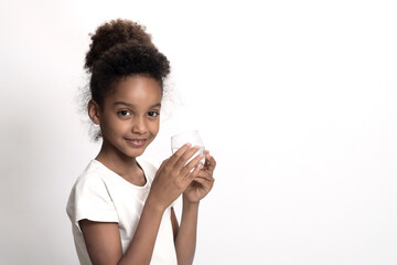 Young girl holds glass of plain drinking water. White studio background. Concept of clean, purified...