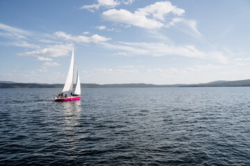 Fototapeta premium A yacht with raised sails quickly sails on the lake. Dynamic shot of rest on the lake.
