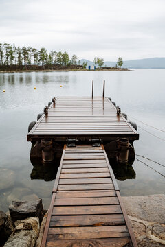 Wooden pier for boats on Lake Turgoyak. Rocky beach.