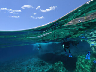 Underwater split photo of beautiful volcanic white rock caves with emerald clear sea