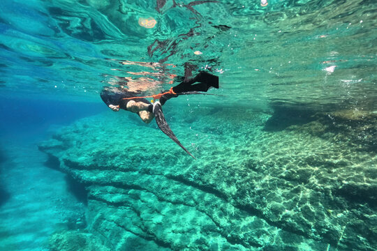 Underwater photo of spear fishing diver in deep emerald exotic paradise bay