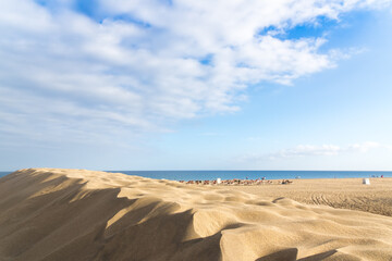 Fototapeta na wymiar Sea coast. Sand dunes. People on the horizon.