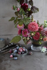 Floral arrangement of autumn flowers in a small glass vase. Dahlias, zinnias, antirriniums, asters and raspberry leaves in a beautiful bouquet on the table.