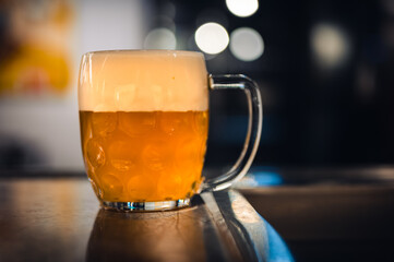 Cold beer glass on a bar or pub desk. Tasty fresh yellow beer of Czech Republic. Dark pub on background.