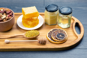 assortment of nuts and assorted dried citrus fruits and fresh floral honeycomb honey and pollen on kitchen wooden board. useful vitamin food for the human body