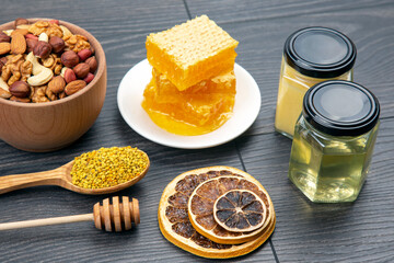 assortment of nuts and assorted dried citrus fruits and fresh floral honeycomb honey and pollen on kitchen wooden board. useful vitamin food for the human body