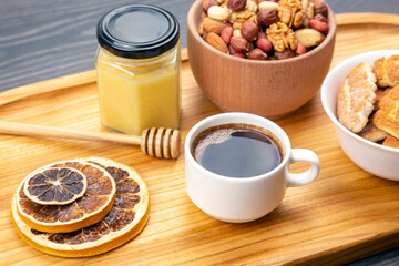 fresh hot coffee with turkey and dried citrus, nuts and honeycomb on a kitchen wooden board. useful vitamin food for the human body