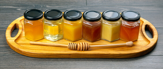 Hexagonal jars with different types and colors of fresh flower honey and a honey spoon. vitamin...