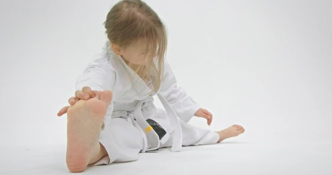 Little baby's foot close up. The girl reaches for her leg to become more flexible.