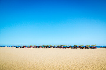 People sunbathe and swim on the beach.