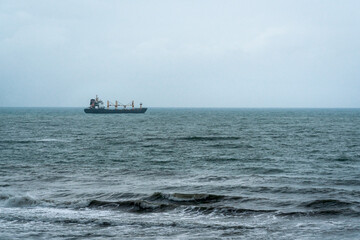 Empty cargo container ship with cranes sailing in a rough ocean during stormy weather, Gandia, Spain