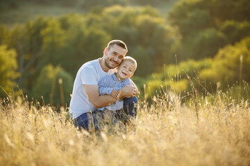 Naklejka na ściany i meble dad plays with his son outdoors in a field among tall grass