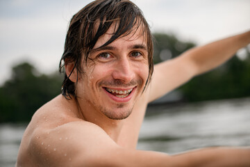 portrait of smiling man with wet brown hair and braces on his teeth