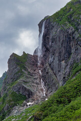 Rocky hill with waterfall falling down into green foliage - Gros Morne National Park - Western Brook Pond
