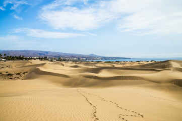 Fototapeta na wymiar Yellow sunset in sand dunes with footprints.