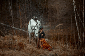 Little girl in riding habit with horse and vizsla in spring forest
