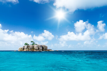 Deserted rocky island in the ocean. Covered with sparse vegetation and trees. The Seychelles.