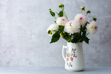 Beautiful autumn bouquet of spherical dahlias in a vase on a table against a background of a gray...