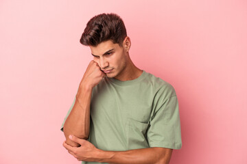 Young caucasian man isolated on pink background who feels sad and pensive, looking at copy space.