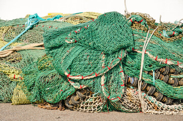 Large tangle of fishing nets on the quay in a fishing harbour on a sunny day