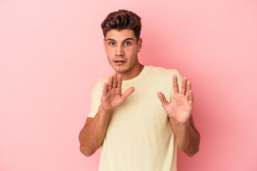 Young caucasian man isolated on pink background rejecting someone showing a gesture of disgust.