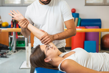 Male hysiotherapist doing elbow extension exercises with a young female patient at a clinic