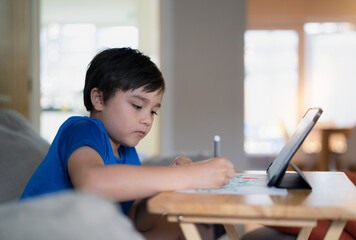 Portrait of preschool kid using tablet for his homework,Child drawing by using digital tablet searching information on internet,E-learning or Home schooling education concept