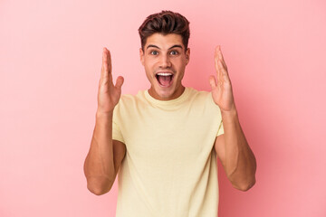 Naklejka premium Young caucasian man isolated on pink background celebrating a victory or success, he is surprised and shocked.