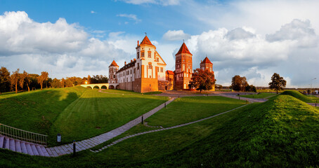 Mir Castle in Belarus at sunset with a blue sky and clouds.Landscape of an old castle against beautiful sky with white clouds on sunset.
