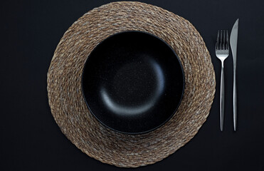 Empty black plate, fork  and knife on black background. Top view.