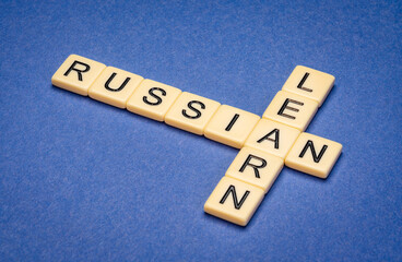 learn Russian crossword in ivory letter tiles against blue textured  paper