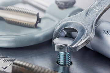 Wrench tightens bolt in steel billet. Spanner, bolt, screw and nuts.