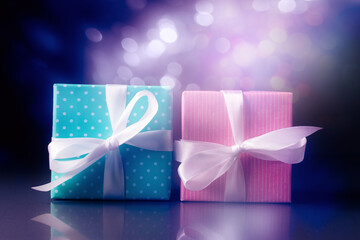 Pink and blue gift boxes over holiday lights