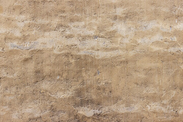 Shabby wall of an old house with uneven crumbling plaster. Yellow-gray abstract texture.