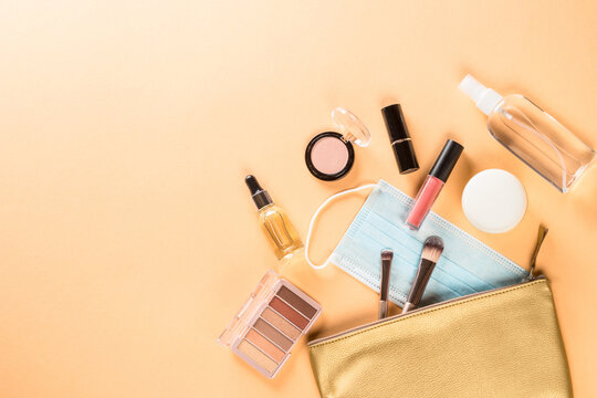 New normal beauty concept. Cosmetic bag with make up products and face mask. Flat lay image with copy space.