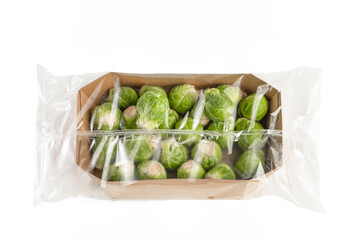 Isolate of fresh Brussels sprouts in paper wrapping and a transparent plastic bag. Brussels sprouts...