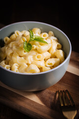 Mac and cheese with basil on top on a rustic wooden board