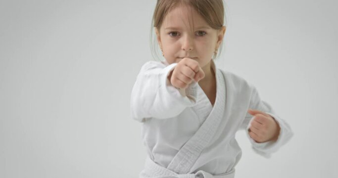 The girl looks intently at the camera and performs blows with her hands in turn. Hit with your hands right in karate.