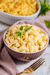 Mac and cheese with basil on top on a rustic wooden board