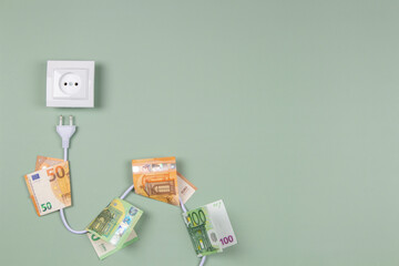 Electric power plug with euro banknotes on it and electric socket on light green background....