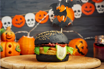 Halloween Spooky Black  Burger. Cheeseburger on Halloween pumpkin head jack lantern holiday food background	